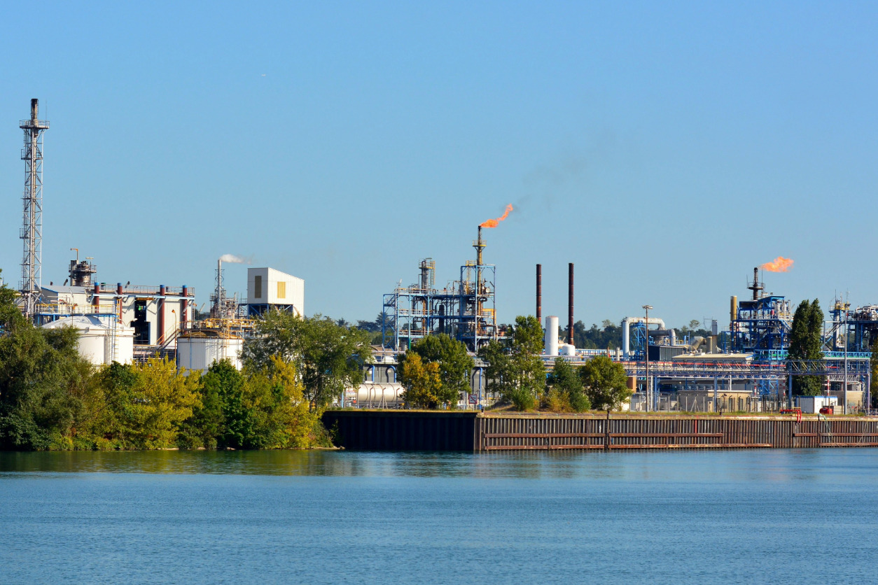 Instalación industrial con antorchas de seguridad y almacenamiento de sustancias peligrosas.