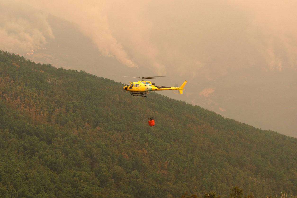 firefighting helicopter dropping water during a forest fire emergency
